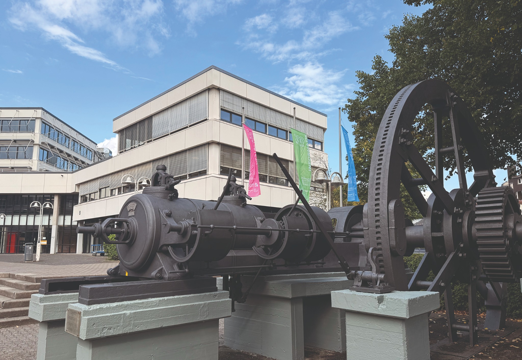 Berufskolleg Technik Siegen mit historischer Dampfmaschine vor dem Schulgebäude